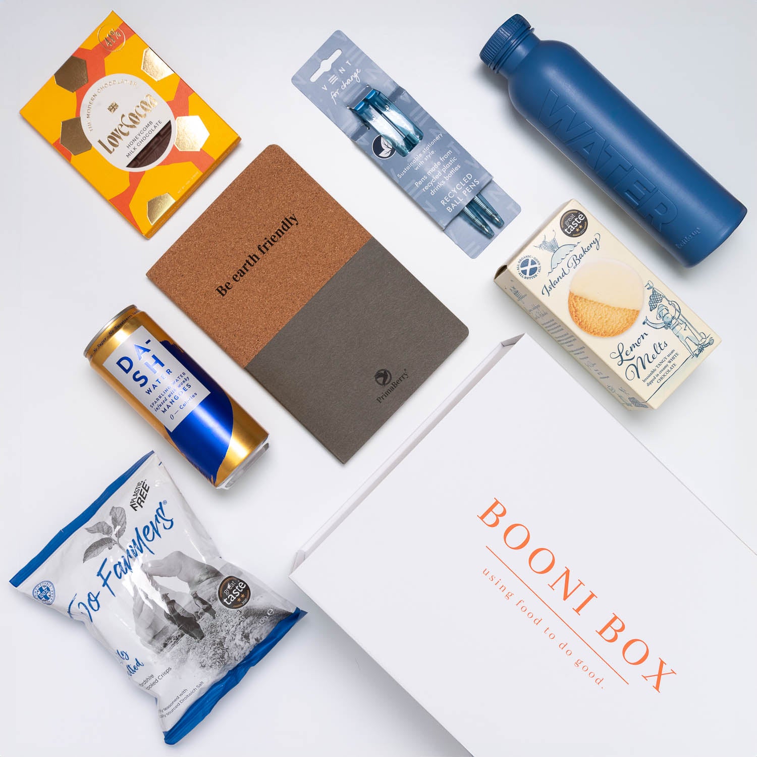 Unpacked Booni Box with crisps, can of water, biscuits, notebook, pens, chocolate and water bottle