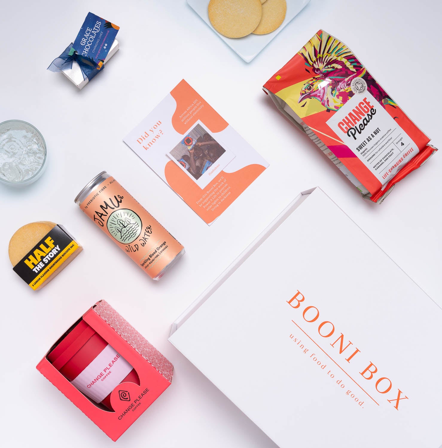 Unpacked Booni Box with reusable coffee cup, canned water, biscuits, ground coffee and chocolates